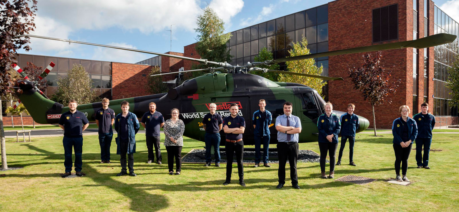Trainees who worked on the G-LYNX restoration stand proudly in front of the helicopter