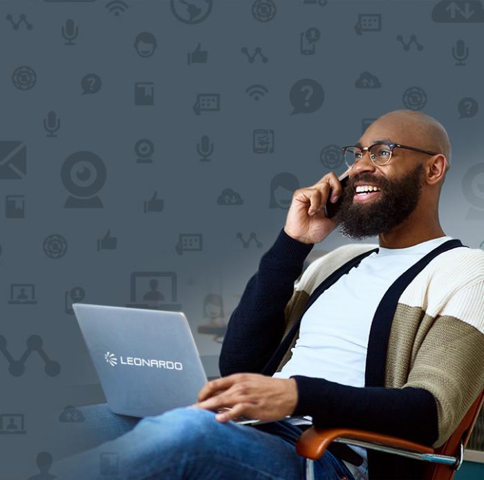 Smiling man using mobile phone and laptop