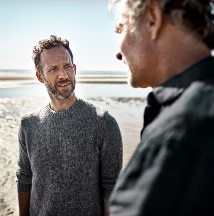Two men speak on the beach
