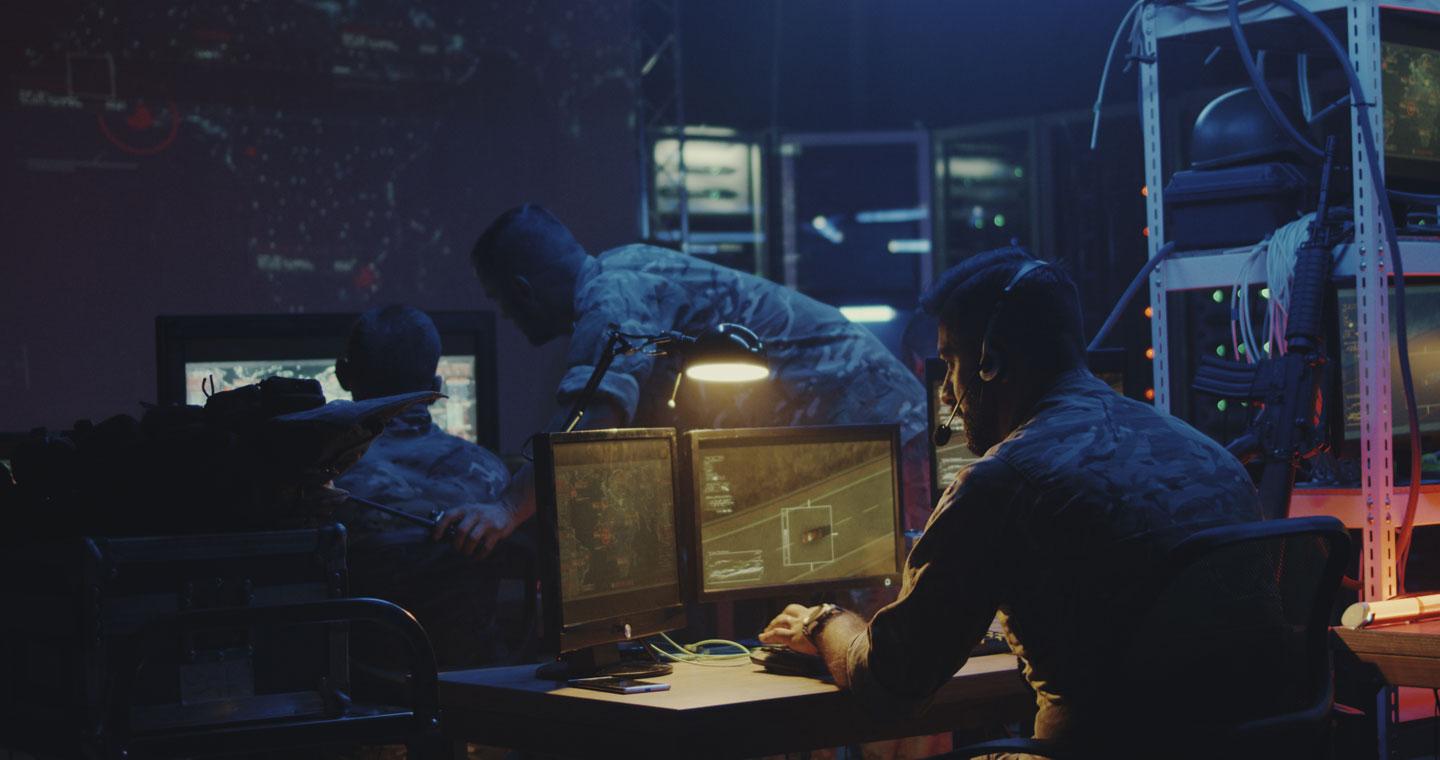 Military personnel work in bunker on screens