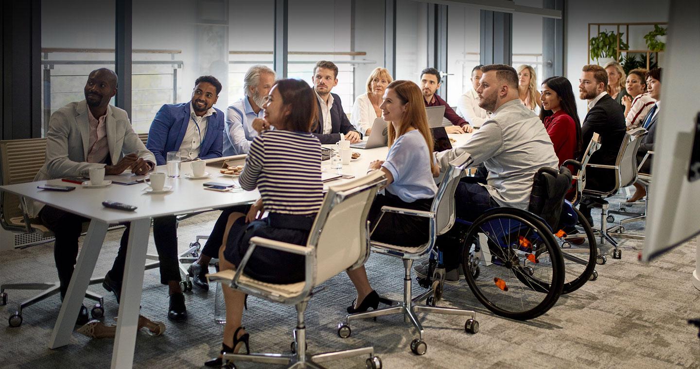A diverse group of colleagues in a meeting, with one person sitting in a wheelchair