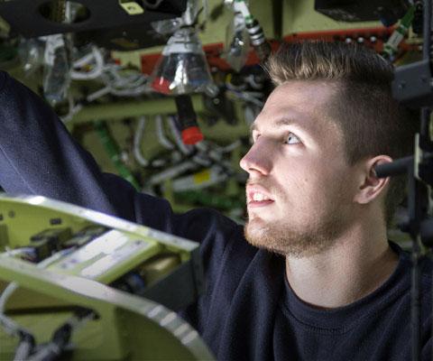 Young white male engineer works inside helicopter at Leonardo