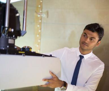 Young Asian male engineer wearing shirt and tie operates machinery