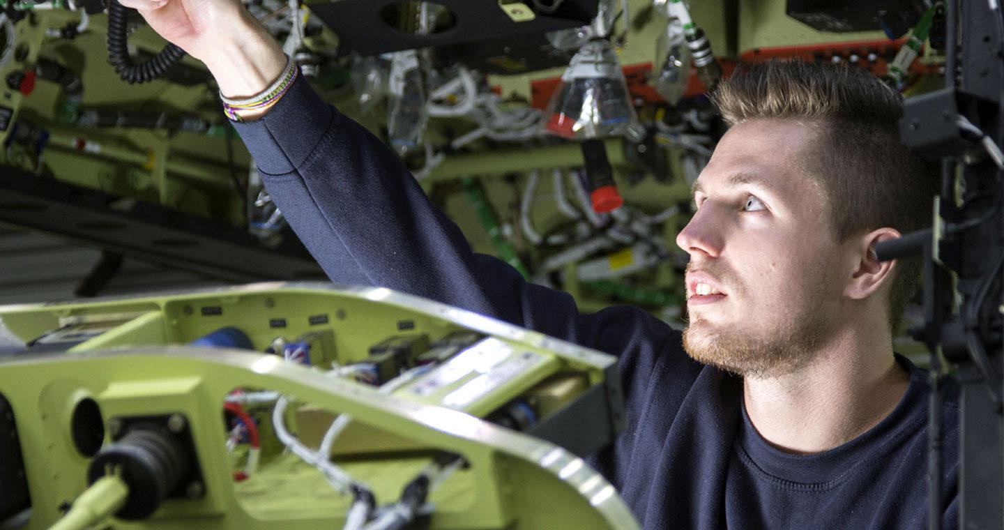 Young white male engineer works on inside of helicopter at Leonardo