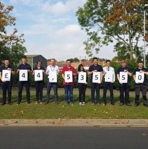 Employees outside holding individual numbers to show fundraising total