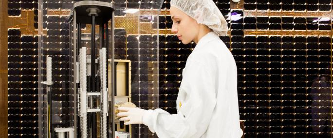 Female employee working in clean room assembling a satellite 