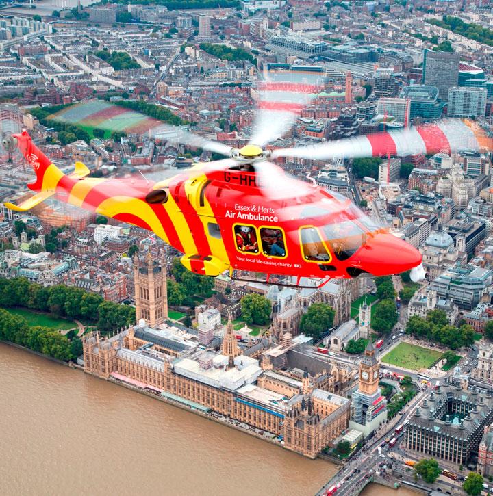 Essex and Herts Air Ambulance AW169 flying over the Thames, with the Houses of Parliament in the background