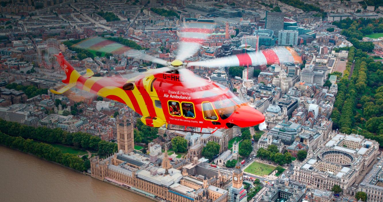 Essex and Herts Air Ambulance flying over the Thames, showing Houses of Parliament below