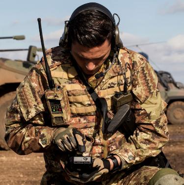 Soldier in the field in battle dress using a hand-held communications device