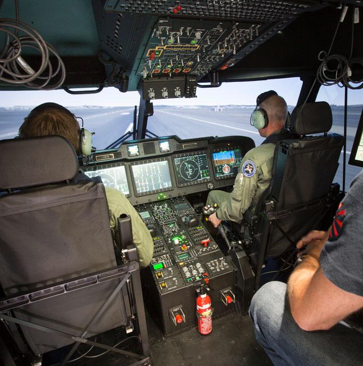 Two aircrew and assessor inside the cockpit of a helicopter full flight simulator 